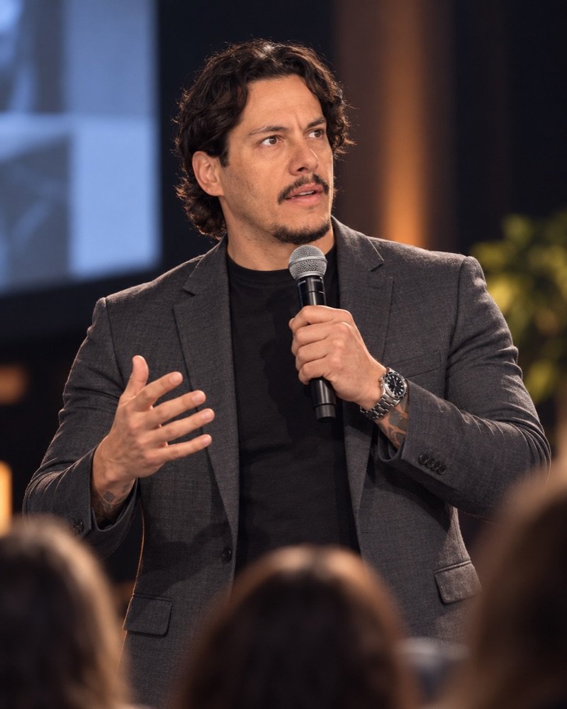 Alexandre Serrão falando ao microfone em um palco