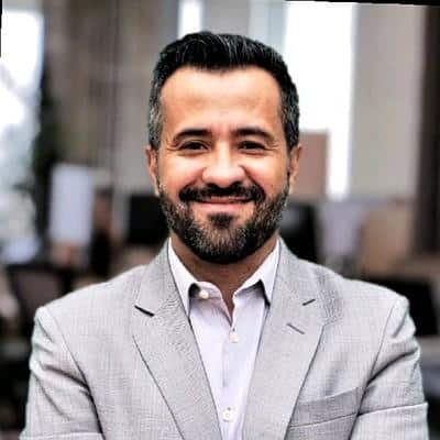 Empresário confiante, vestindo fato cinza ao frente de escritório moderno, transmitindo sucesso na aceleração de negócios comerciais.